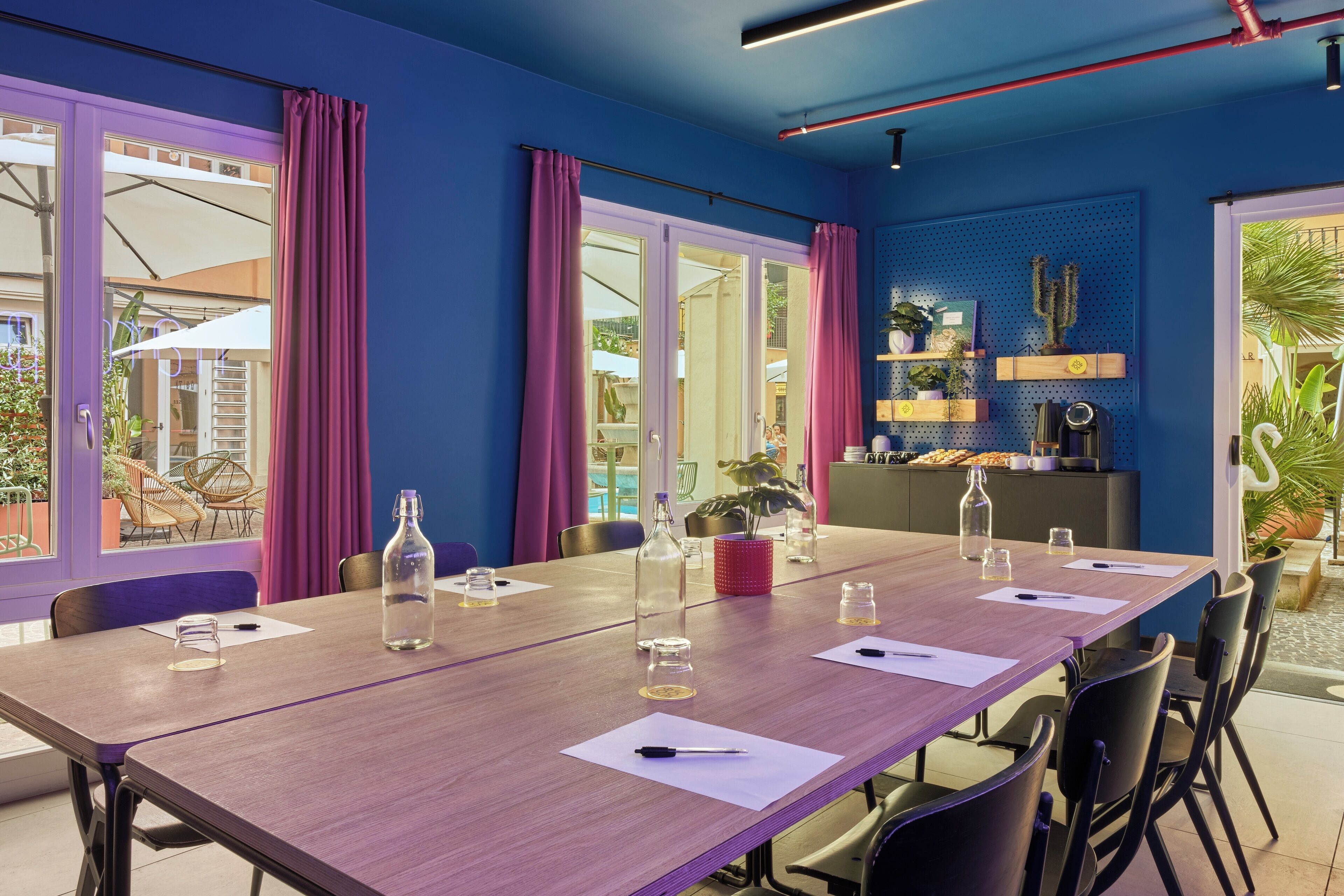 Un salón de conferencias con una mesa larga, sillas y una estación de café.
