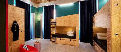 A room with bunk beds, a red chair, and a wooden wall with numbered sections.