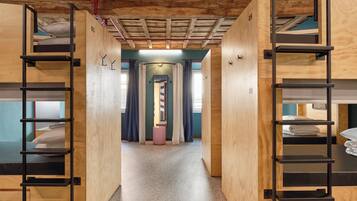 Un pasillo con literas a ambos lados, paredes de madera y una puerta central que da a otra habitación.