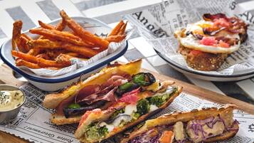 A meal with sandwiches and fries on a table with newspaper.