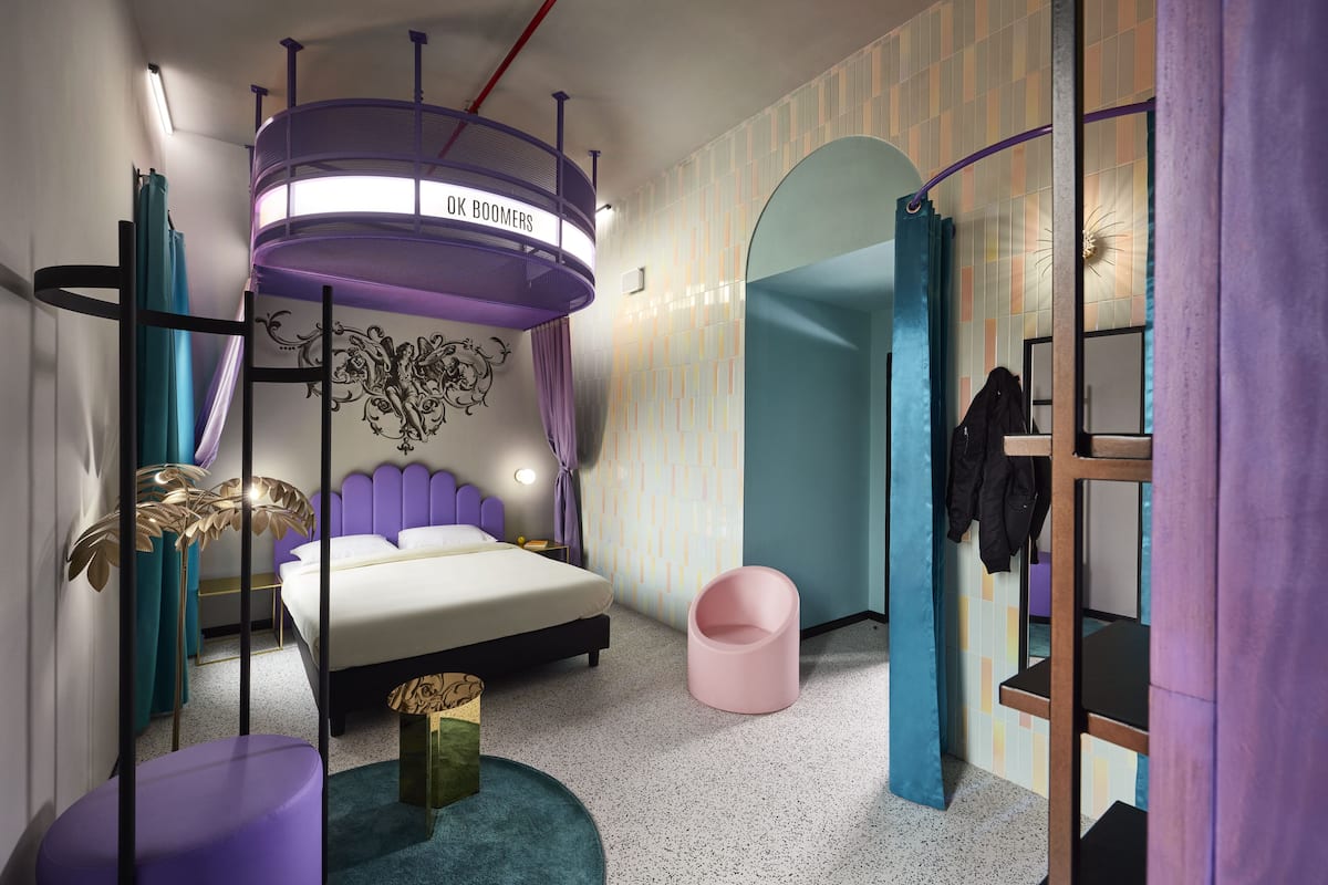 Ein modernes Schlafzimmer mit einem Bett, einer runden Deckenleuchte, einem rosa Sessel und einem Kleiderschrank.