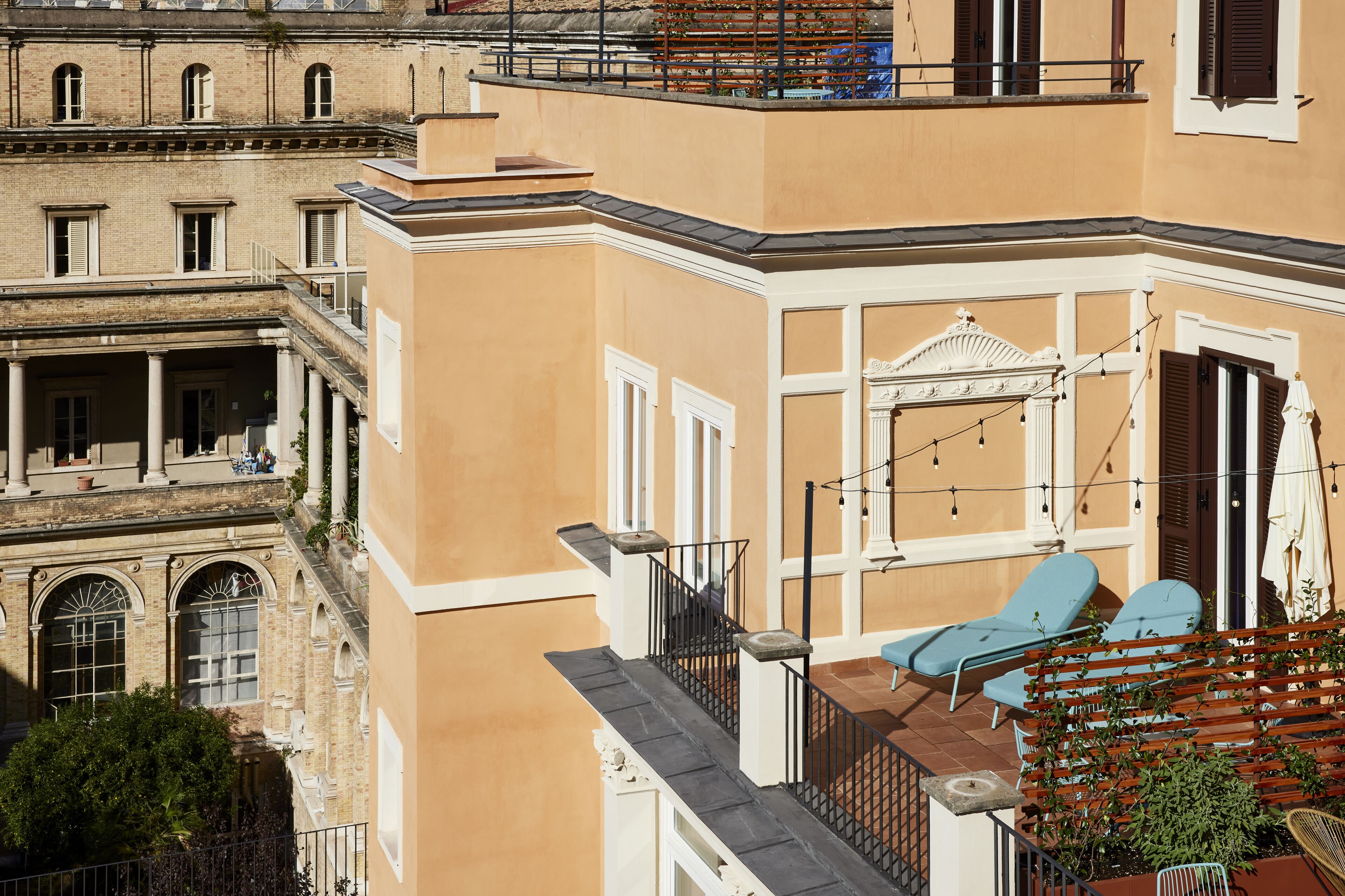 A corner building with a balcony, a small outdoor seating area with two chairs, and a door with a decorative arch.