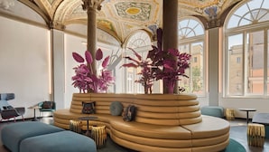 A spacious lobby with a curved seating area, large windows, and ornate ceiling artwork.