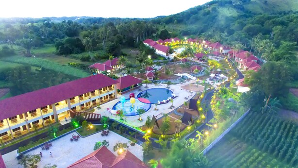 Luchtbeeld van een resort met meerdere gebouwen, een zwembad en aangelegde tuinen.