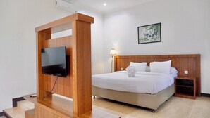 Een hotelkamer met een bed, een aan een houten constructie bevestigde televisie, een nachtkastje en een wandlamp.