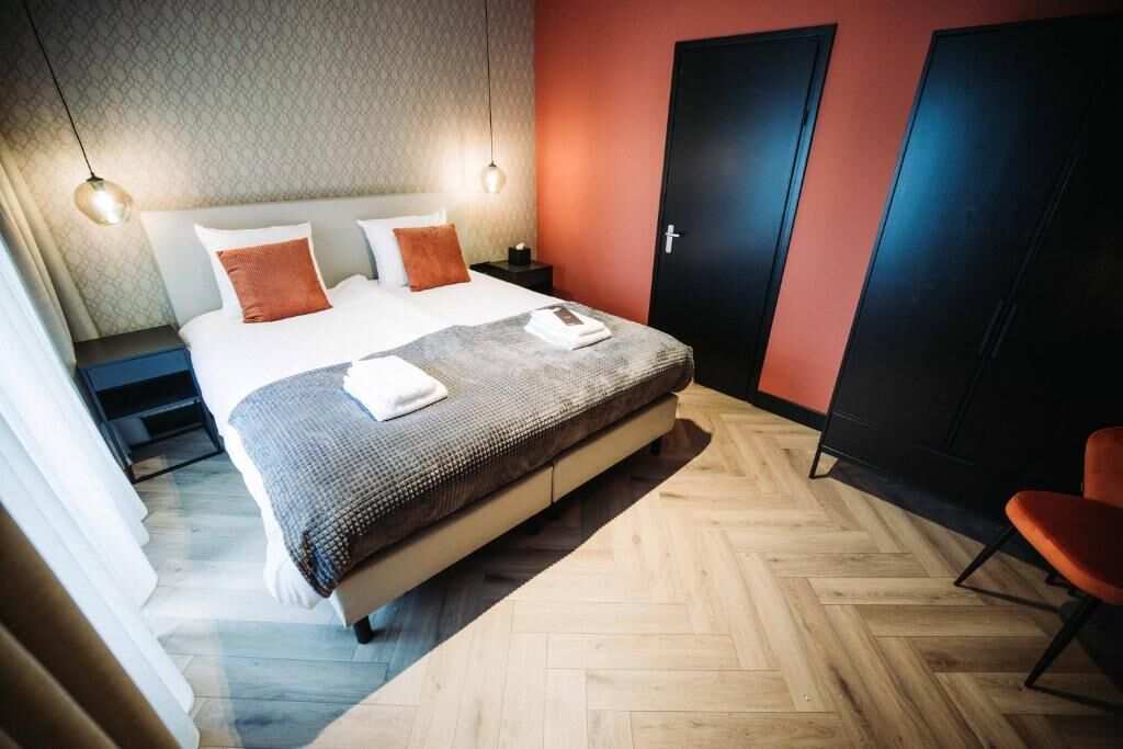 Un dormitorio ordenado con una cama grande, una mesita de noche, un armario y una silla.