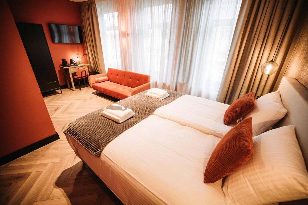 Une chambre d’hôtel avec un grand lit, un bureau, une chaise et un téléviseur fixé au mur.