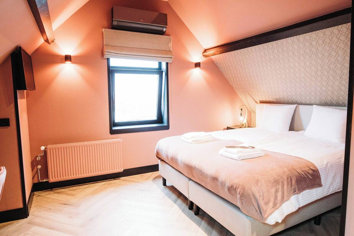 Un dormitorio con una cama, una ventana, un radiador y una lámpara en el techo.