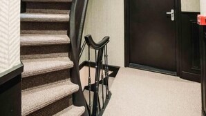A carpeted staircase with a handrail, a door labeled "106", and a small table with a chair. - Boutique Hotel Lupo  (Vlissingen)