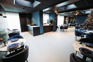 Un comedor moderno con una isla central, paredes azul oscuro y un árbol de Navidad.