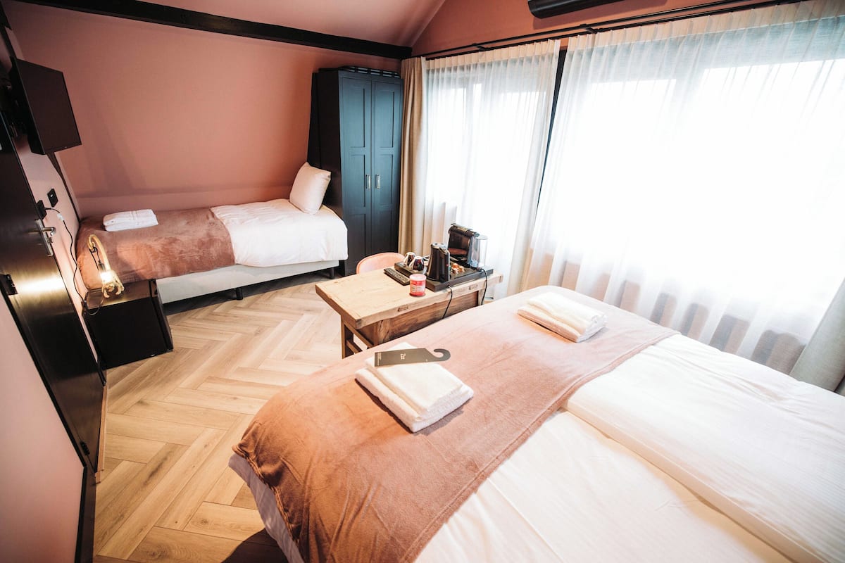 Habitación de hotel con dos camas, un escritorio con cafetera, armario y televisor.