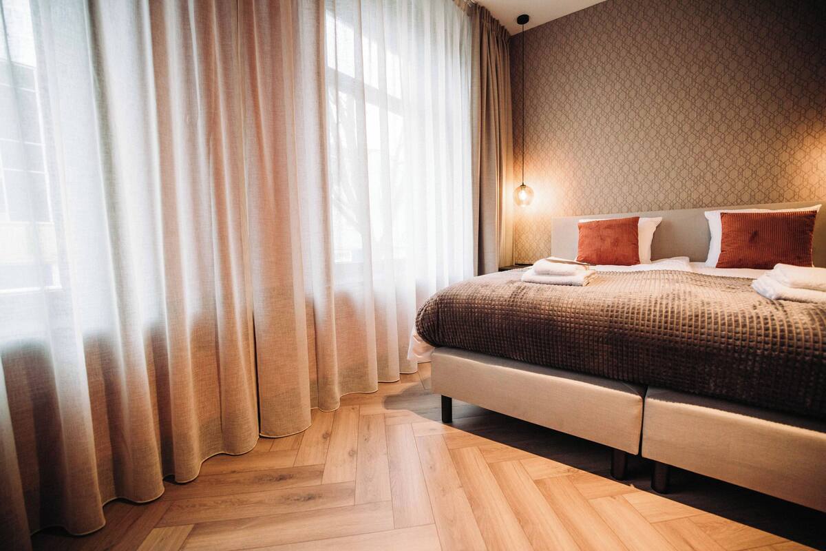 Habitación de hotel con una cama grande, piso de madera y pared con diseño.