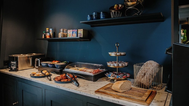 A kitchen area with a marble countertop, a toaster, a bread bin, a meat display, and a variety of condiments and jars on shelves. - Boutique Hotel Lupo  (Vlissingen)