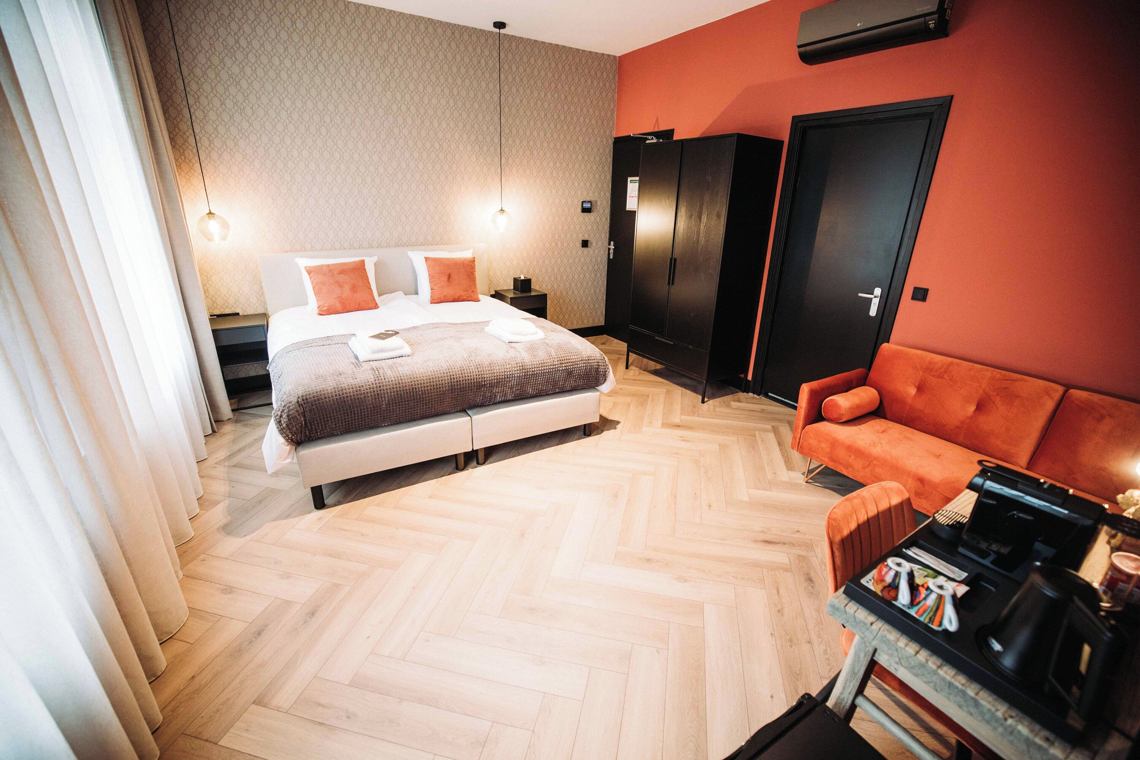 A modern hotel room with a large bed, a sofa, a wardrobe, and a coffee table.