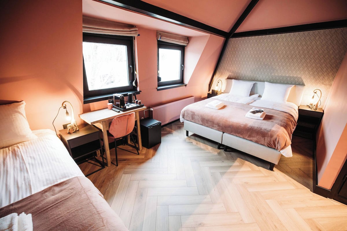 Un dormitorio con cama, escritorio, silla y dos mesitas de noche con lámparas.