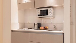 Une cuisine moderne équipée d’un four à micro-ondes encastré, d’un grille-pain et d’un panier à fruits posé sur le plan de travail.