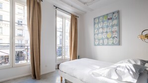 Une chambre à coucher avec un lit, de grandes fenêtres et une vue sur la ville.