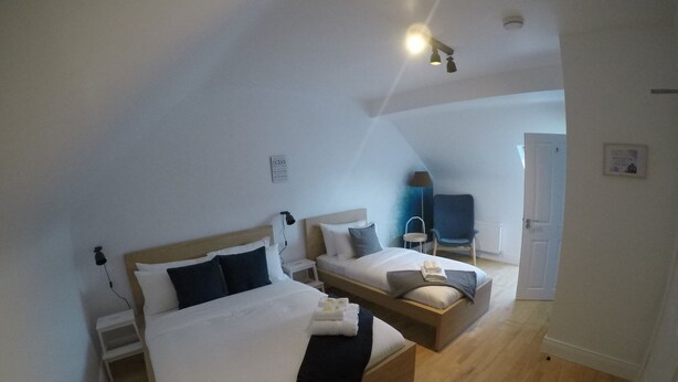 A bedroom with a large bed, a smaller bed, a chair, and a desk. - Triple room with ensuite bathroom (Portmagee)