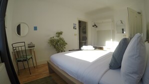 A bedroom with a bed, a chair, a small table, a plant, and a mirror. - Double room with en-suite bathroom (Portmagee)