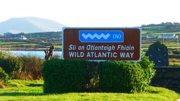 Ein Schild für die Wild Atlantic Way, im Hintergrund eine malerische Landschaft.