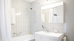 Un baño moderno con bañera, ducha y tocador con espejo.