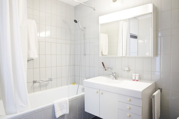 Un baño moderno con bañera, ducha y tocador con espejo.