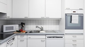 Una cocina moderna con armarios blancos, microondas, fregadero y lavavajillas.