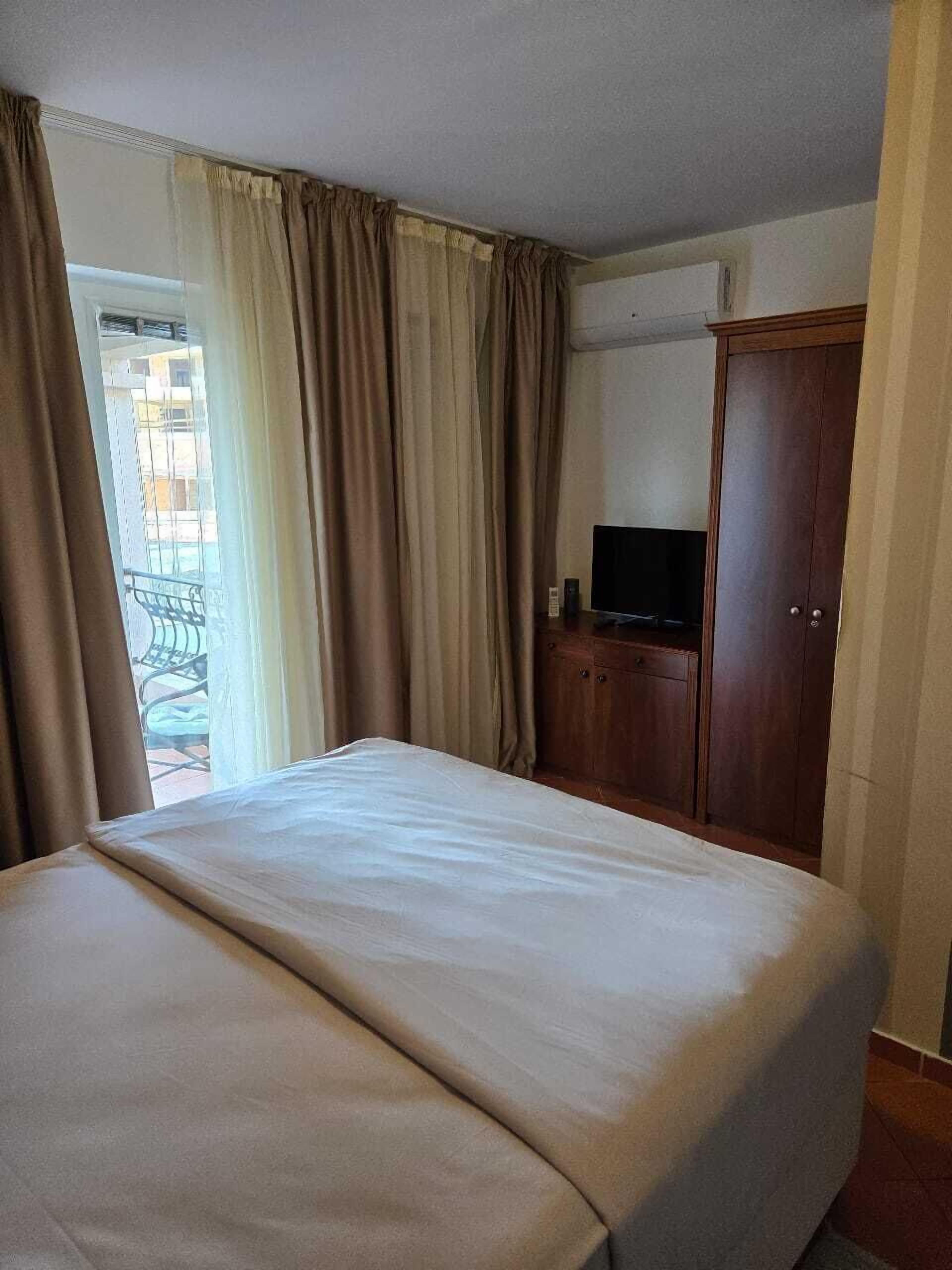 A hotel room with a bed, a television, and a wardrobe.