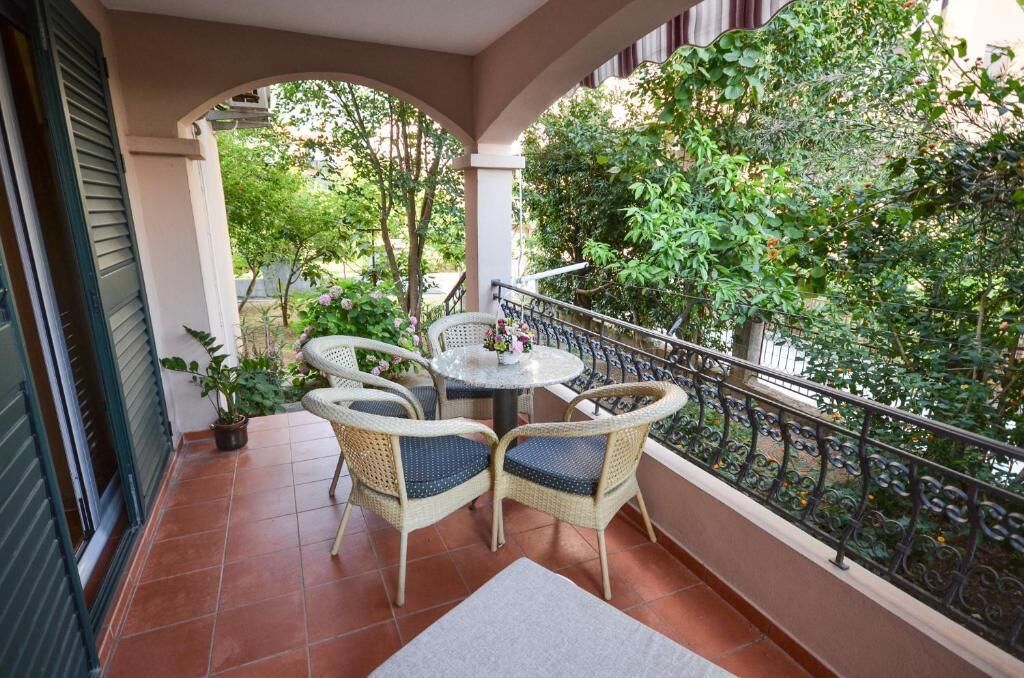 A balcony with wicker furniture, a small table, and potted plants.