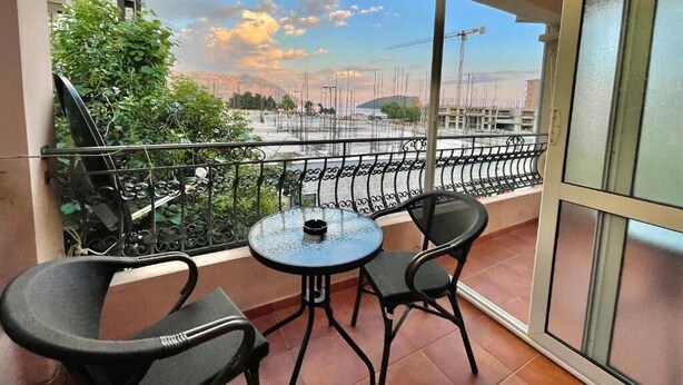 A balcony with a table and chairs, a view of a construction site, and a building in the background. - Apartments Petkovic Budva (Budva)