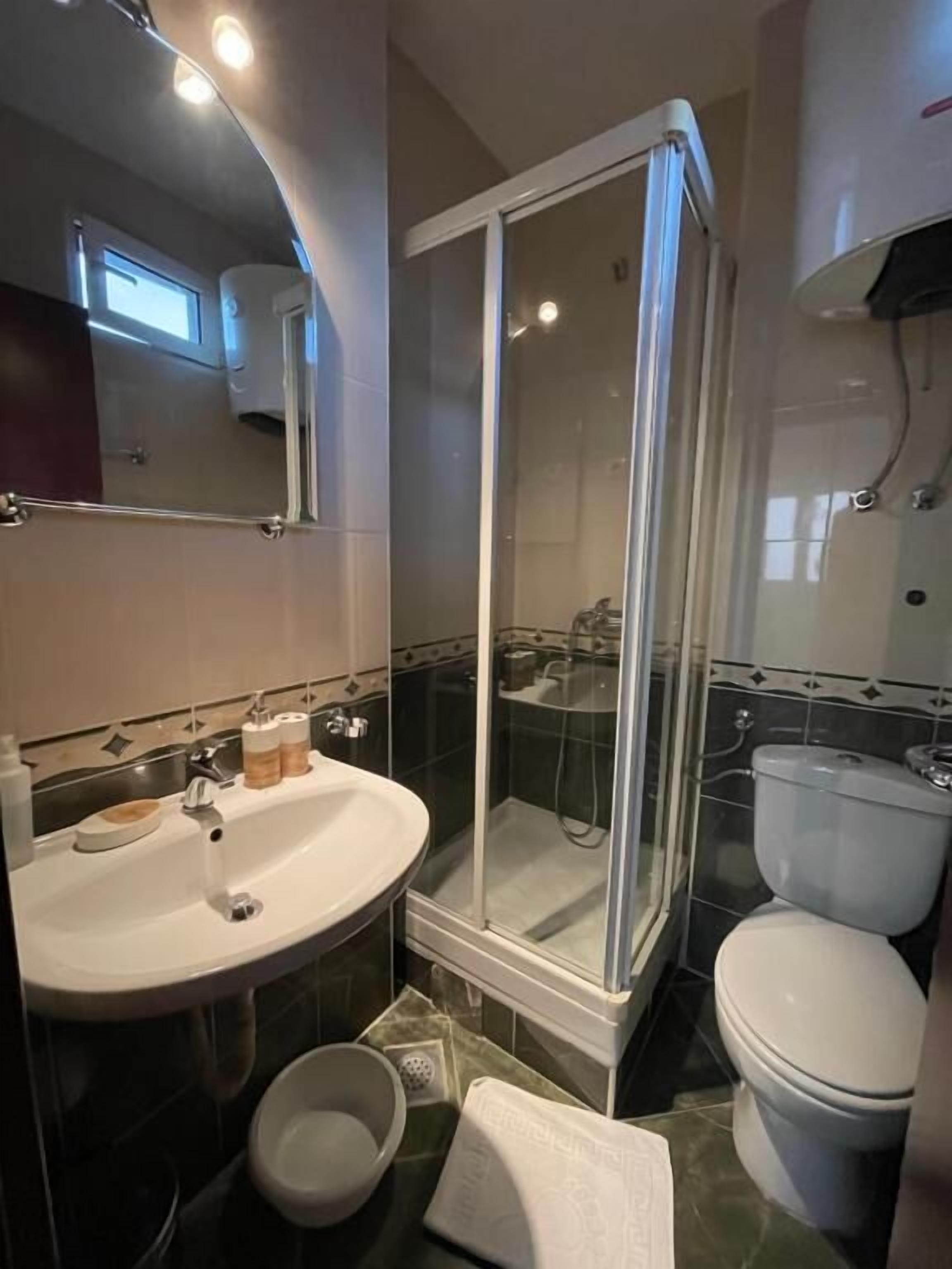 Ein Badezimmer mit Duschkabine, Waschbecken mit Spiegel und Toilette.