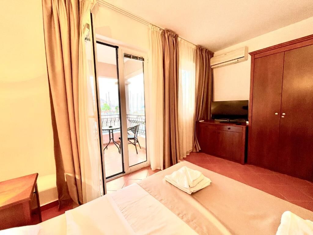 Une chambre d’hôtel équipée d’un lit, d’une télévision, d’une armoire et d’une porte-fenêtre coulissante donnant sur un balcon.