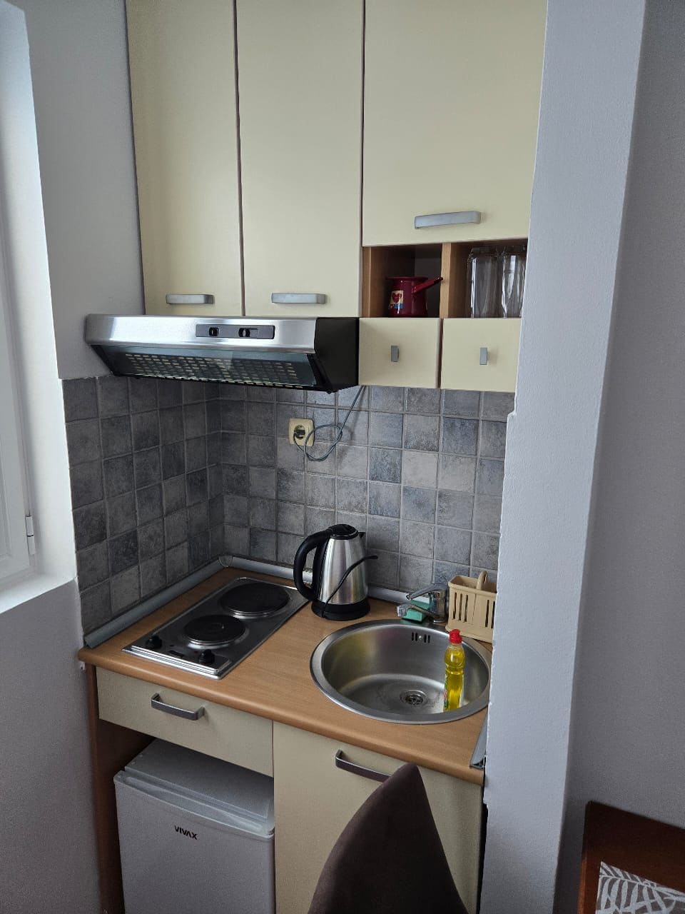 Une cuisine de taille réduite, équipée d’une cuisinière, d’un évier et d’un petit réfrigérateur.