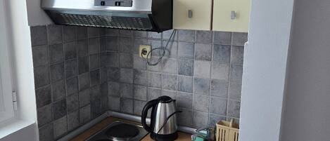 Une cuisine de taille réduite, équipée d’une cuisinière, d’un évier et d’un petit réfrigérateur.