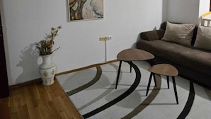 A modern living room with a brown sofa, a white vase with flowers, and a large abstract painting on the wall. - Apartments Petkovic Budva (Budva)