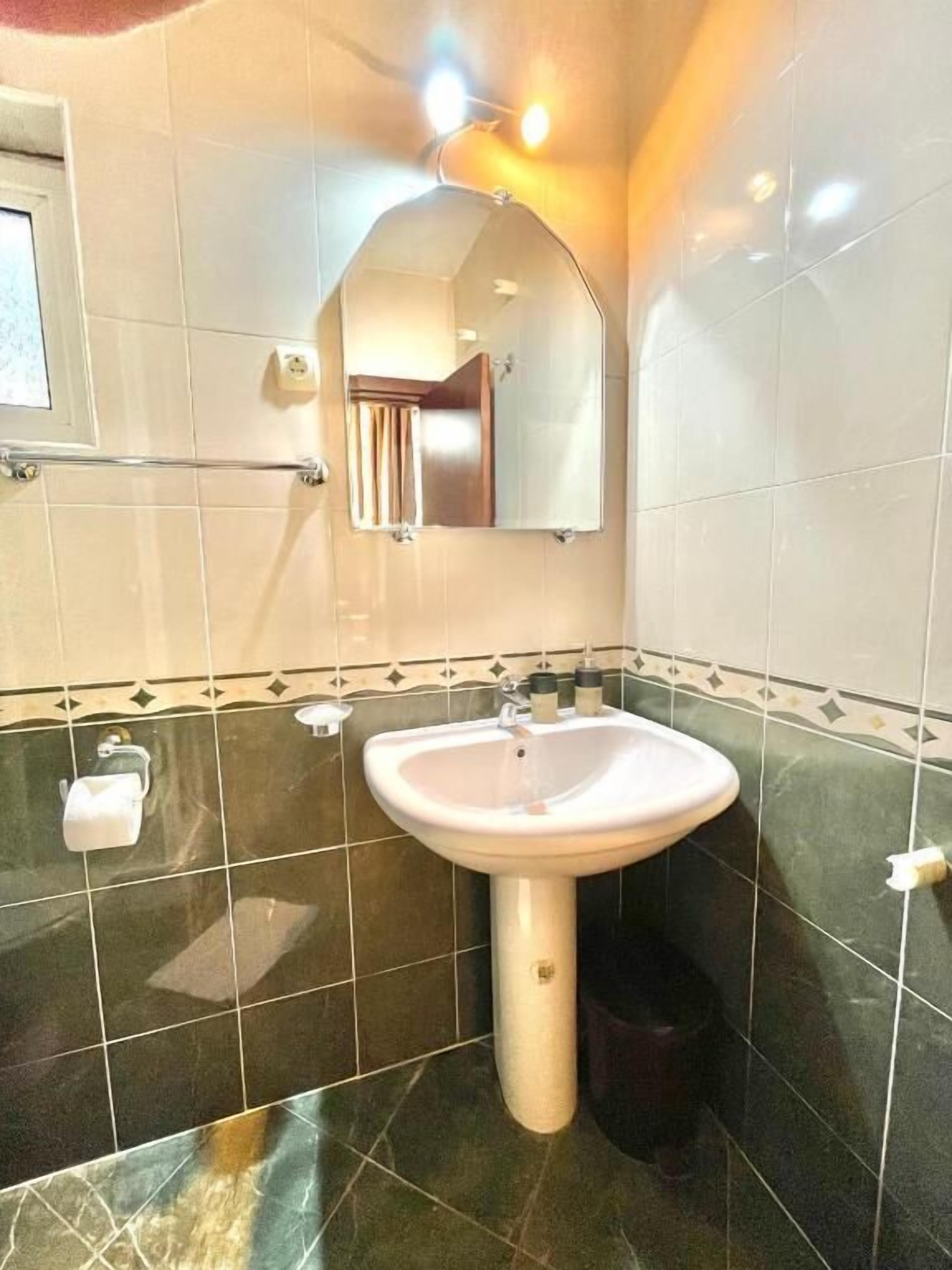 A bathroom with a white sink, a mirror, and a towel rack.