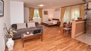 A compact living space with a sofa, a bed, a dining area, and a kitchenette. - Apartments Petkovic Budva (Budva)
