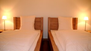 A symmetrical room with two beds, each with a wooden headboard and a bedside lamp. - Nest - Baarerstrasse 55 (Zug)