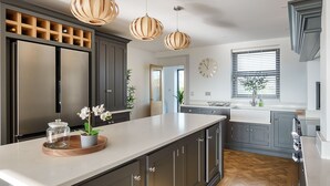A modern kitchen with a large island, dark cabinets, and pendant lighting.