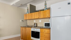 A kitchen with wooden cabinets, a Bosch refrigerator, a stove, and a microwave. - Caprice Court 6 (Cape Town)