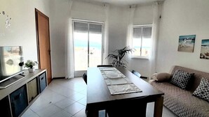 En moderne stue med spiseplads, der indeholder et fjernsyn, en sofa og et bord dækket til spisning.