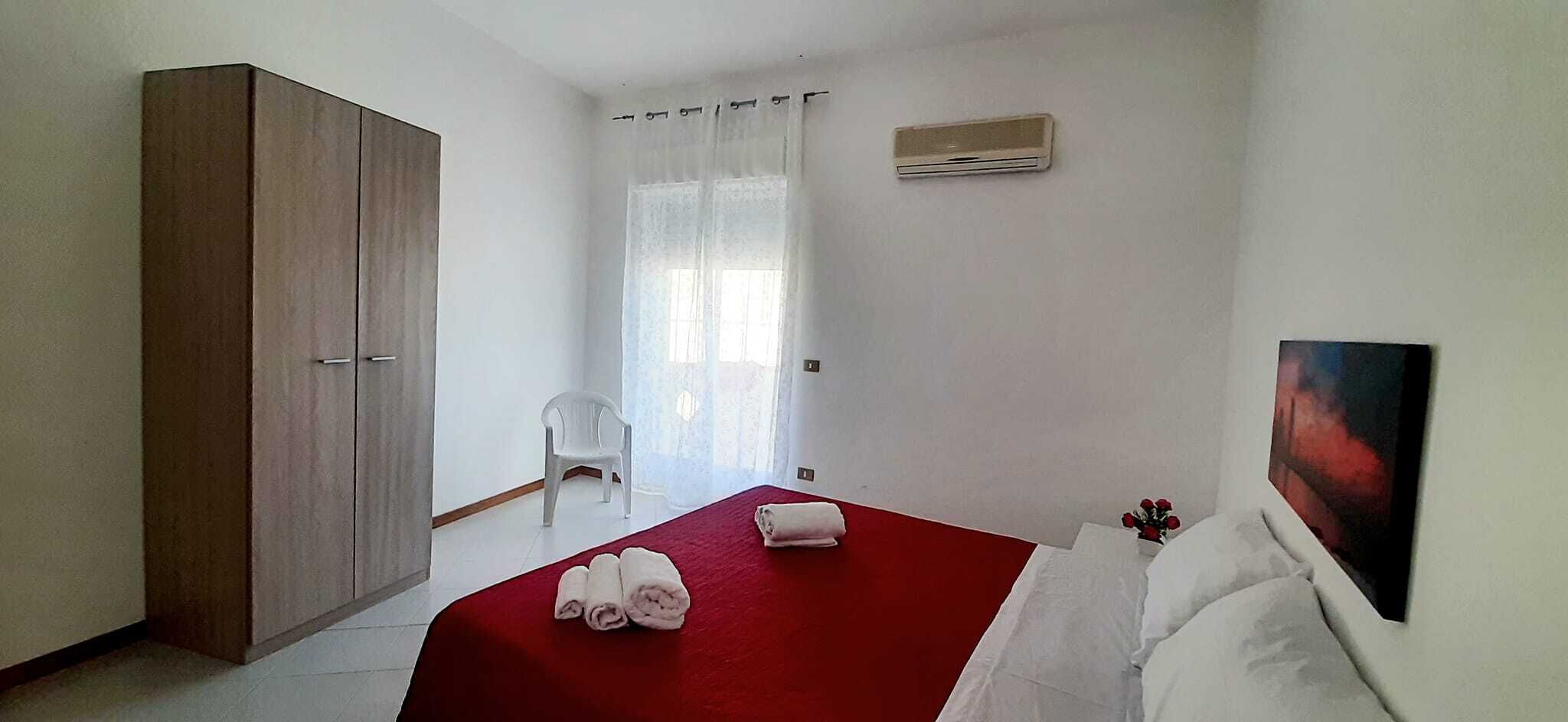 A hotel room with a bed, a wardrobe, a chair, and a painting on the wall.