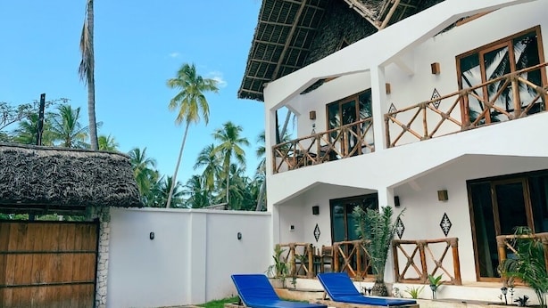 A two-story building with a pool, surrounded by palm trees. - Mambo Cabana (Pwani Mchangani)
