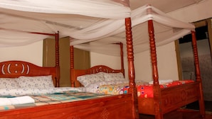 Ein Himmelbett mit Baldachin, einem Holzkopfstück und einer zudeckenden Bettdecke mit Blumenmuster.