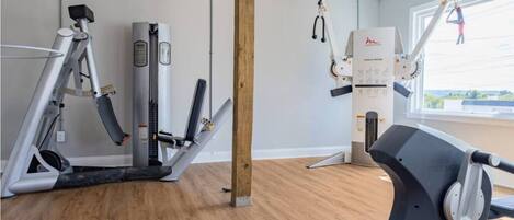 A gym with cardio machines, a cable cross trainer, and a pull-up bar.