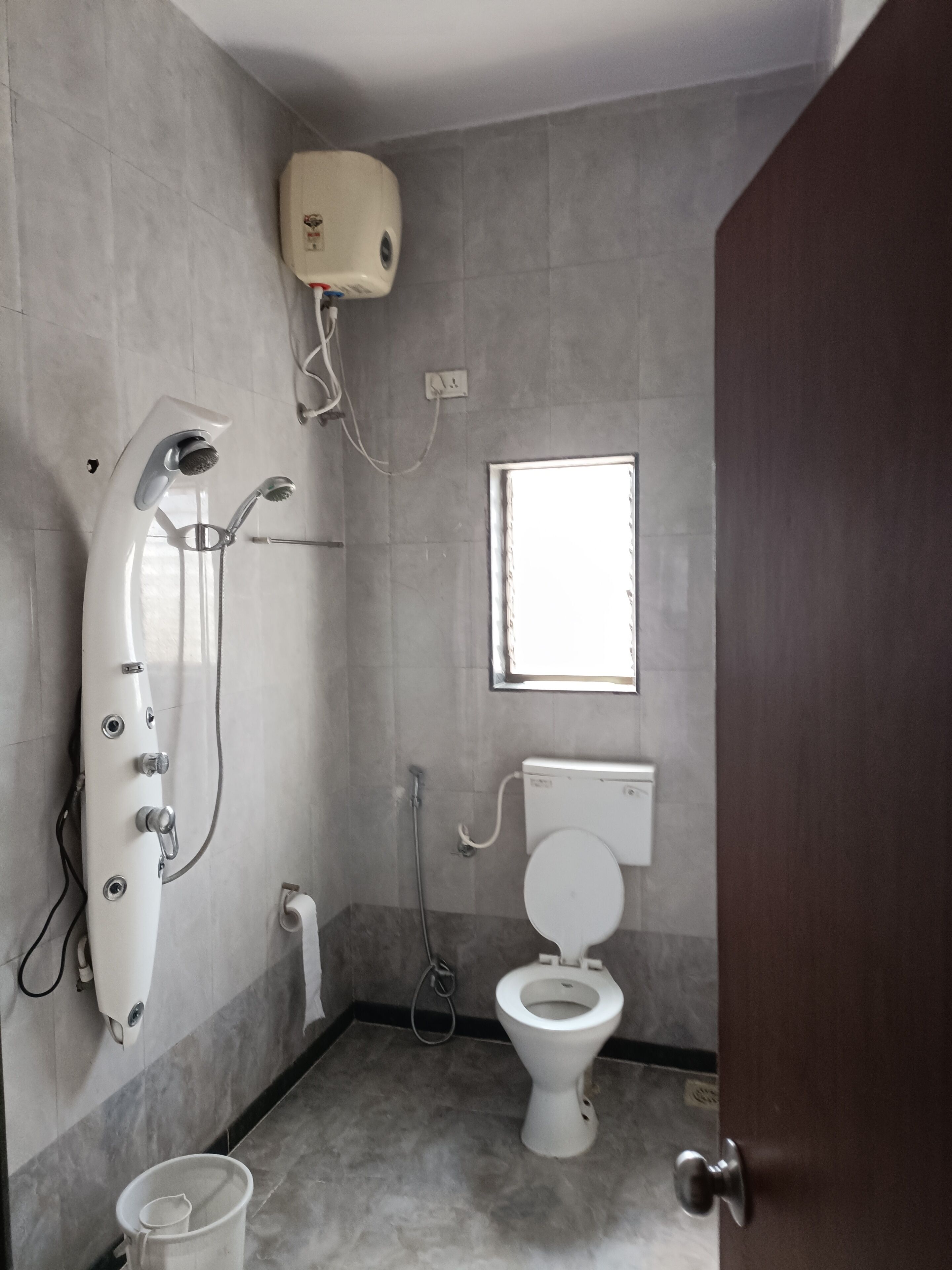 A bathroom with a shower, toilet, and a window.