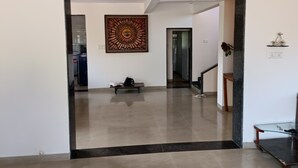 A hallway with a large artwork on the wall, a bench, and a staircase. - Vue Villa (Igatpuri)