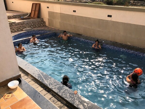 Una piscina con escalones de cerámica que bajan al agua, rodeada por un muro bajo.