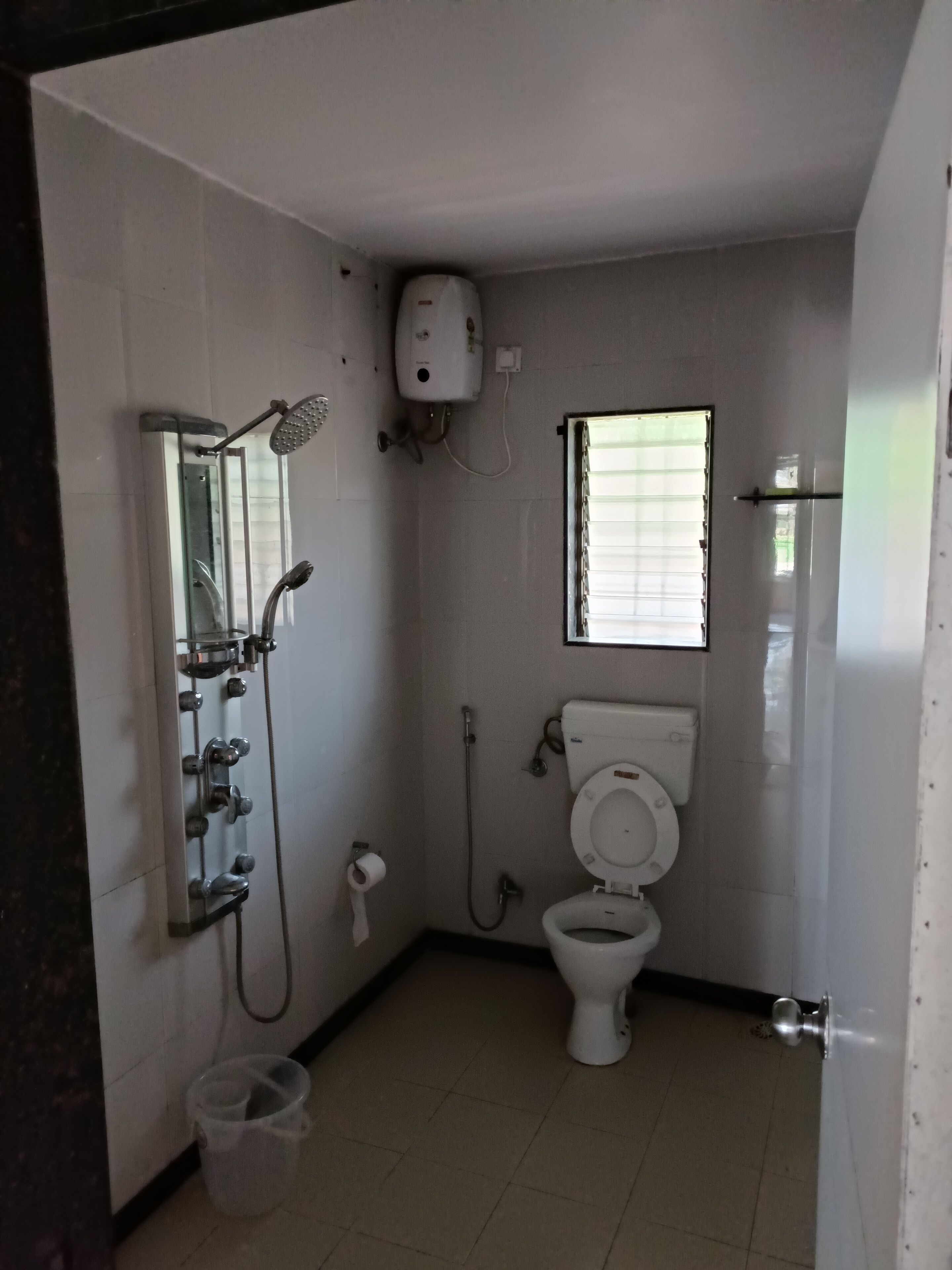 Une petite salle de bain propre, équipée de toilettes, d’une douche et d’une fenêtre.