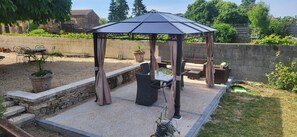 A covered patio area with a pergola, outdoor furniture, and potted plants.